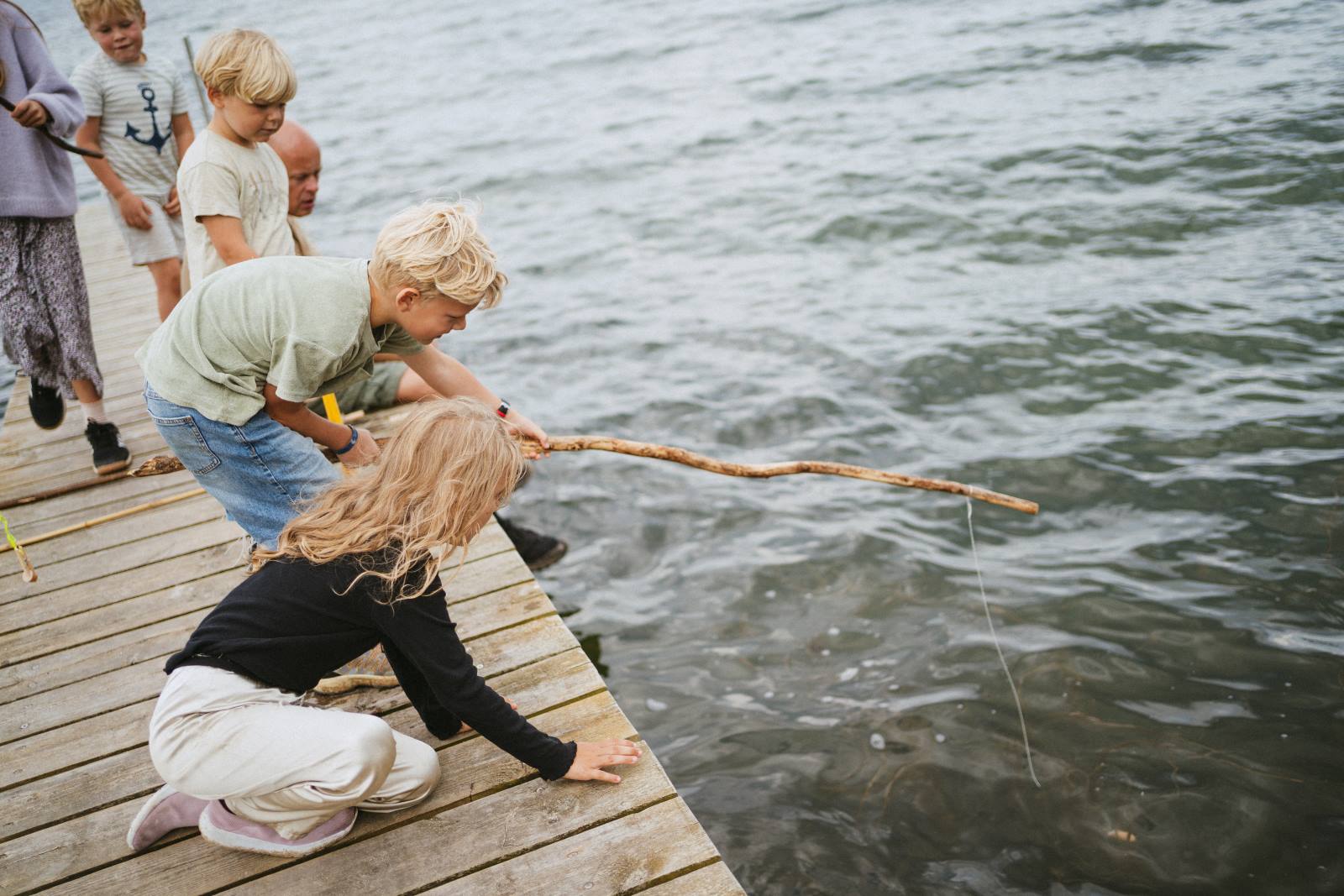 Børn fisker efter krabber ved stranden