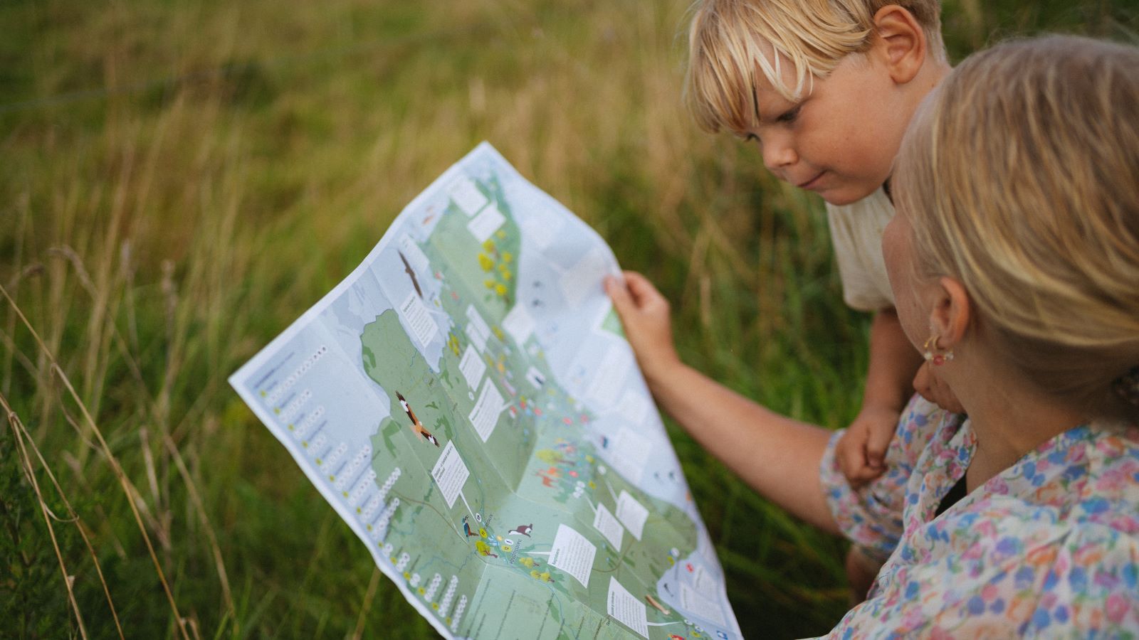 Børn og voksen kigger i friluftsguiden