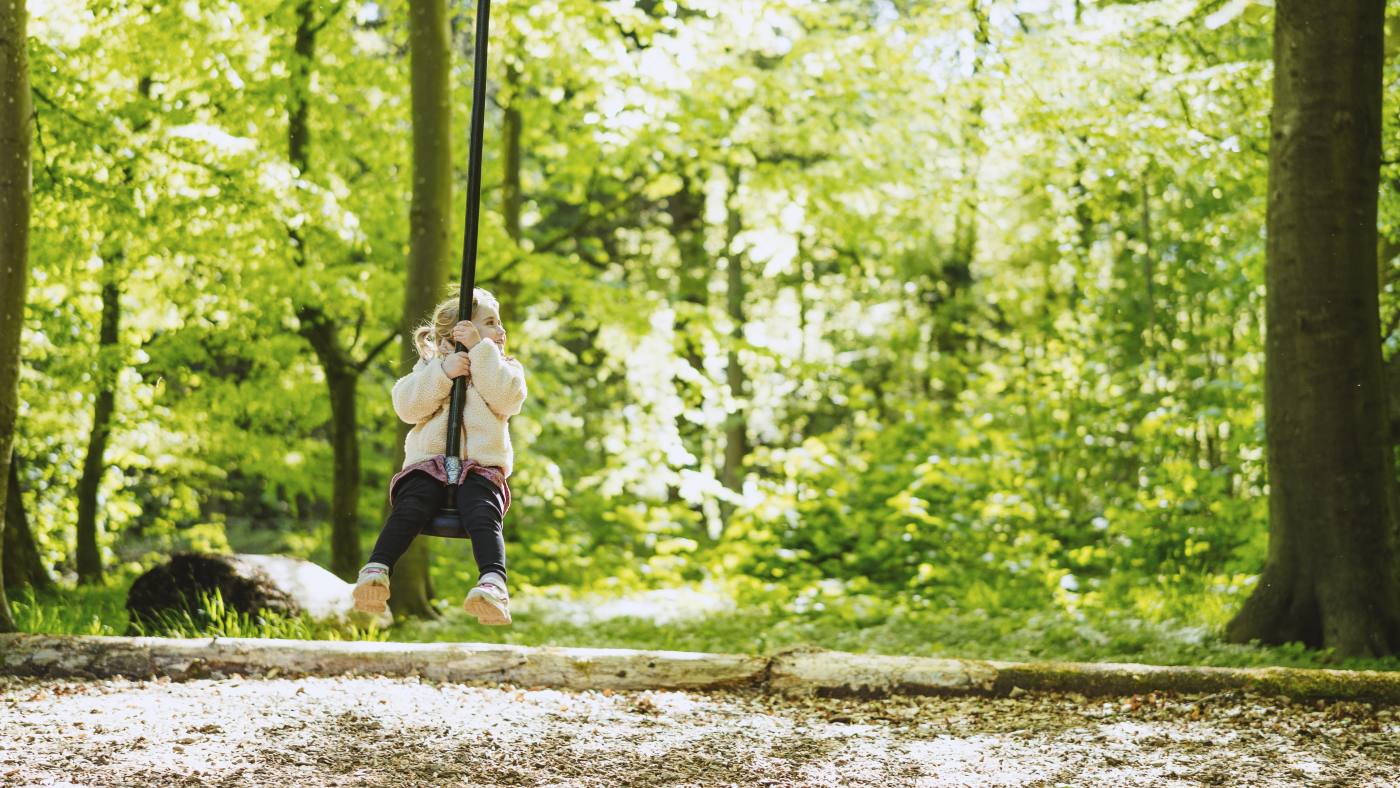 Pige på gynge på naturlegeplads
