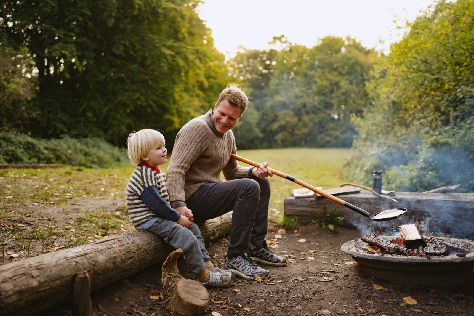 Far og søn sidder ved bålet på shelterplads